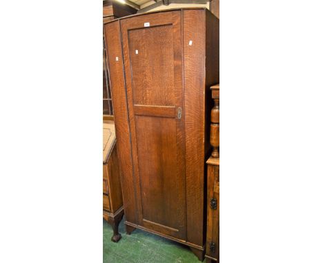 A 1930's oak hall robe, arched top panelled door, bracket feet. 185cm high x 77cm wide x 43cm deep.