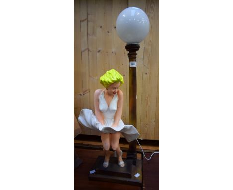 A novelty table lamp in the form of Marilyn Monroe, in iconic pose, standing beside a street lamp with glass globe, 73cm appr