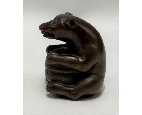 Japanese carved wood netsuke carved in the form of a seated bear holding a pot, height 4cm