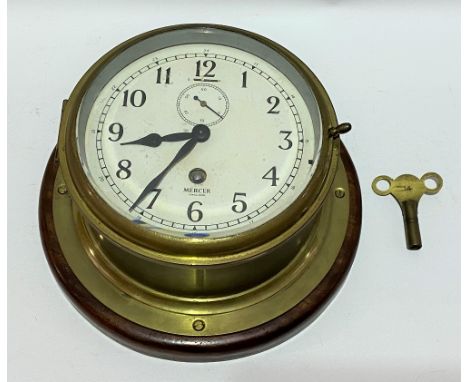 A brass bulkhead timepiece by Mercer England, the 6 inch white enamel dial with black Arabic numerals signed Mercer, the sing