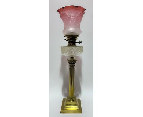 Brass Corinthian column oil lamp with cranberry blush etched glass shade and with cut glass reservoir, height 72cm