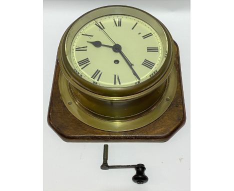 A good single fusee ship's brass bulkhead wall clock, with 8 inch cream enamel dial with black roman numerals, the movement s