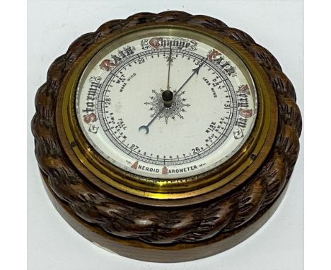 An aneroid barometer within a carved oak rope twist case, diameter 19cm. 