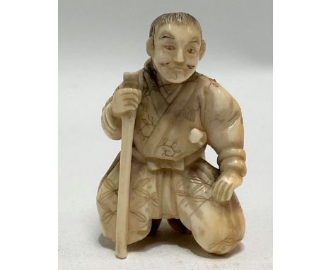 Meiji period Japanese ivory carved netsuke in the form of a kneeling gentleman with stick, height 4cm