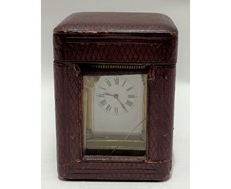 A French brass carriage timepiece with travel case, the 3.5cm white enamel dial with black roman numerals, within an anglaise
