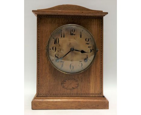 An oak cased German two-train mantle clock with 5in dial with black Arabic Numerals and within an arched inlaid case, the mov