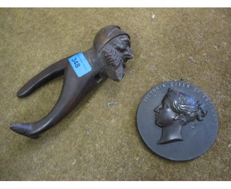 A treen nutcracker in the form of a Grindlewald, together with a composition plaque 'Victoria Queen of England' 