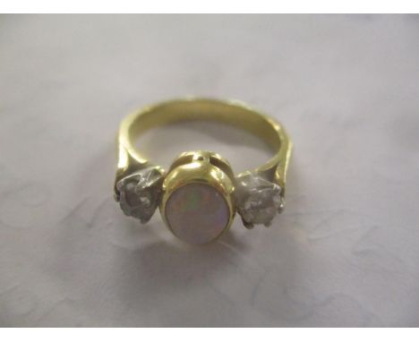 A yellow metal ring inset with an opal flanked by two old cut diamonds 4.6g 