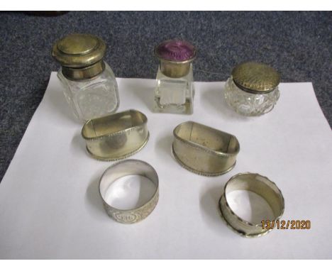 A small group of silver and silver plated items to include four napkin rings and three dressing table pots one having a lilac