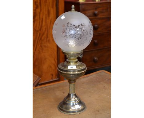 A brass oil lamp with etched glass globe