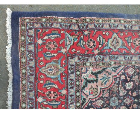 A LARGE EASTERN WOOLLEN RUG / CARPET, with a central floral cartouche on a mainly dark blue ground with an all over floral pa