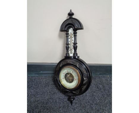A carved antique ebonised cased barometer with brass enamel dial 