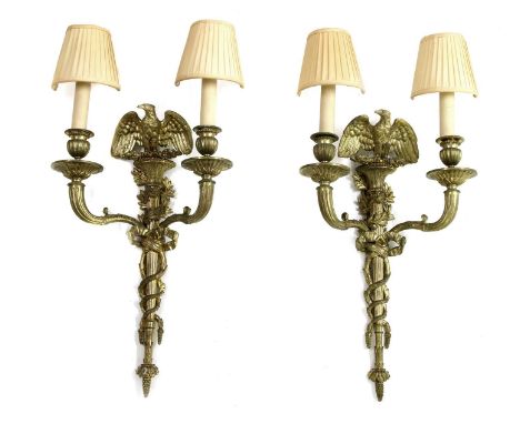 A pair of Empire design gilt metal wall lights, each with two scrolling sconces to a reeded mount, surmounted by an eagle wit