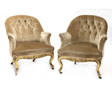 A pair of Victorian giltwood salon tub chairs,the iron-framed button upholstered backs over carved scrolling legs,72cm wide10