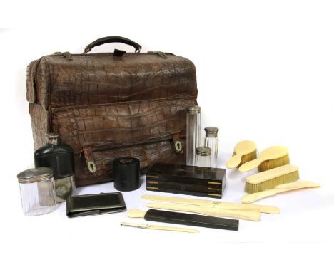 A crocodile skin travelling vanity case,late 19th century, containing a number of silver-topped bottles and jars, a silver-mo