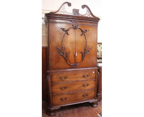 A good-quality reproduction mahogany linen press in the Chippendale 'style,' with pierced fret-work swan-neck pediment, folia