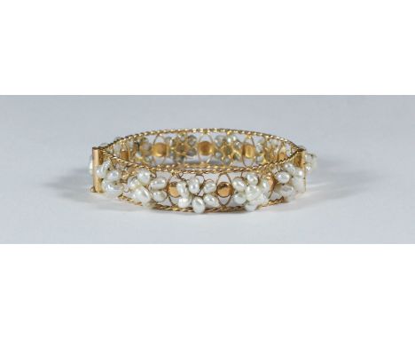 A yellow metal (tests as approximately 16ct gold) hinged bangle, decorated with eleven small clusters of freshwater pearls. G