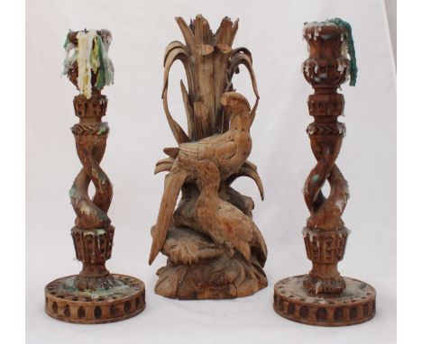 An antique carved limewood sculptural candlestick modelled as birds amidst foliage, 44cm high, together with a pair of carved