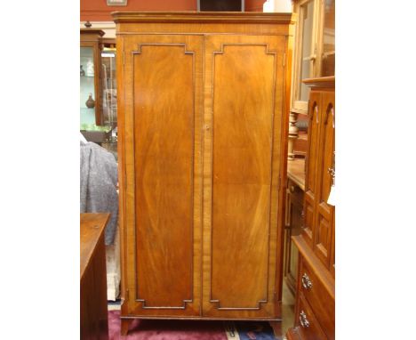 An early 20th Century mahogany wardrobe, with moulded cornice, canted sides and a pair of crossbanded doors with outline moul