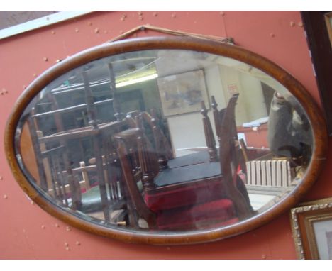 An Edwardian oak framed oval bevelled glass wall mirror. 