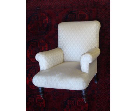 A late Victorian upholstered easy armchair
with rectangular roll over back and scroll arms,on turned forelegs and ceramic cas