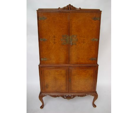 A Queen Anne style burr walnut drinks cabinet, the upper section with a pair of cupboard doors enclosing an interior with mir