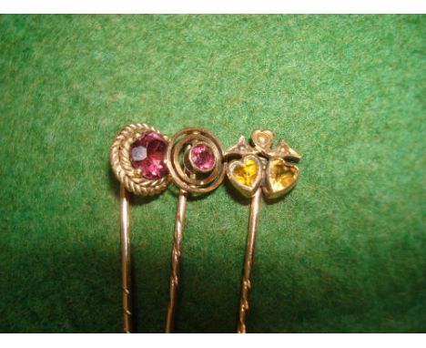 Three Edwardian yellow metal stone set stick pins, one set with two heart shaped citrines and split pearls, another set with 