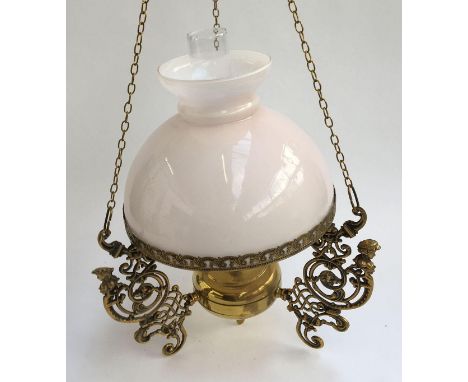 A hanging brass oil lamp with pierced spandrels, light pink milk glass shade and glass chimney 