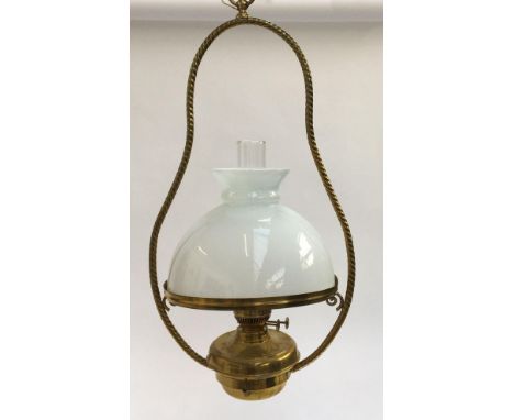 A hanging brass oil lamp with rope twist detail, milk glass shade and glass chimney 