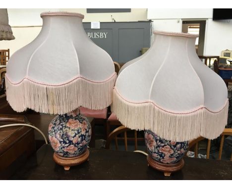 A pair of oriental ceramic table lamps, on carved bases, with tasseled shades 