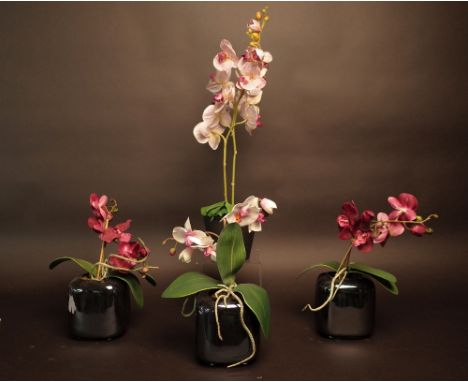 A set of three faux pink orchids in metallic ceramic pots and another potted faux orchid. 