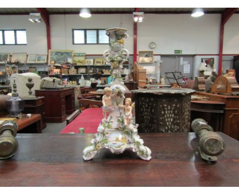 A Rococo style porcelain candlestick with scenes of boats, applied cherubs and floral detailing, 41cm high