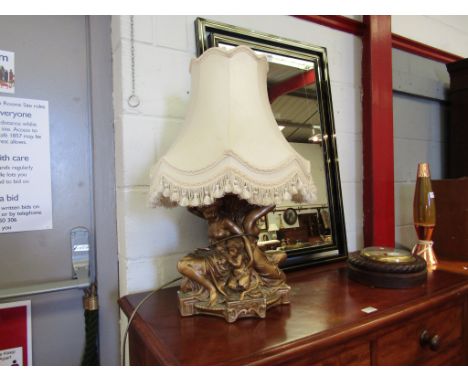 A highly ornate plaster figured lamp base in gilt semi naked females and putti, 66cm tall with shade
