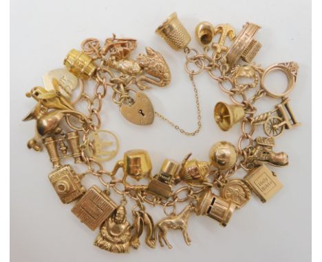 A 9ct gold charm bracelet with thirty 9ct and yellow metal charms to include a retro tape recorder, swan and helicopter and o