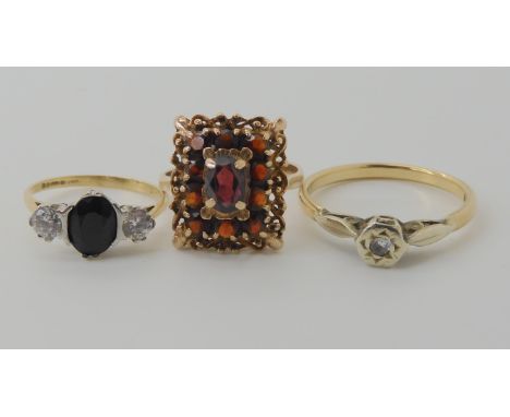 A 9ct gold sapphire and cz three stone ring, size H1/2, a 9ct garnet cluster ring size K1/2, and a 9ct illusion set diamond r