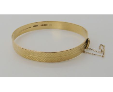 A 9ct gold bangle with bright engraved finish, inner diameter approx 5.5cm, weight 13.2gms Condition Report: Available upon r