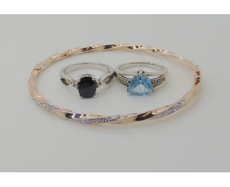 A silver blue and white sapphire ring, a silver trilliant cut blue topaz ring and a bangle Condition Report: Not available fo