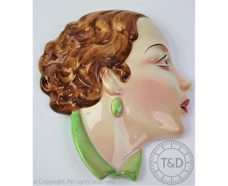 A Cope &amp; Co No.1 Art Deco ceramic wall mask, depicting a lady in profile with brown curly hair, in a green collar, impres