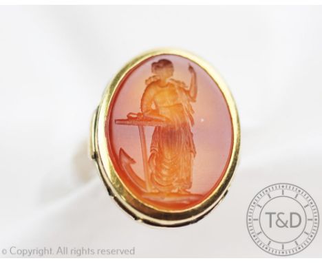 A large intaglio set ring, the carnelian coloured intaglio engraved with a standing female figure beside an anchor, within ye
