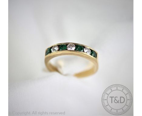 An emerald and diamond half eternity ring, the four circular cut emeralds interspersed with three diamonds within channel set