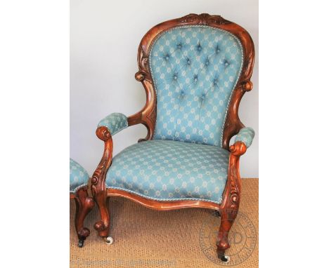 A Victorian carved walnut button back salon chair, with patterned blue upholstery, with scroll end arms and scroll legs, 98cm