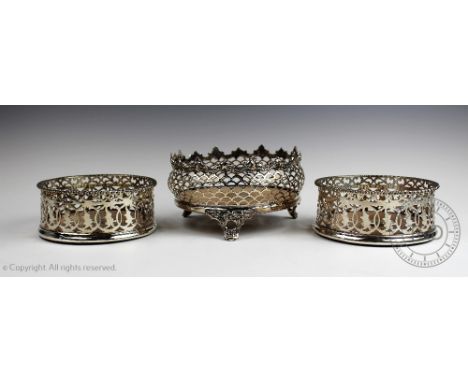 A pair of white metal bottle coasters, each of circular design with pierced gallery, turned wood base and central inset panel