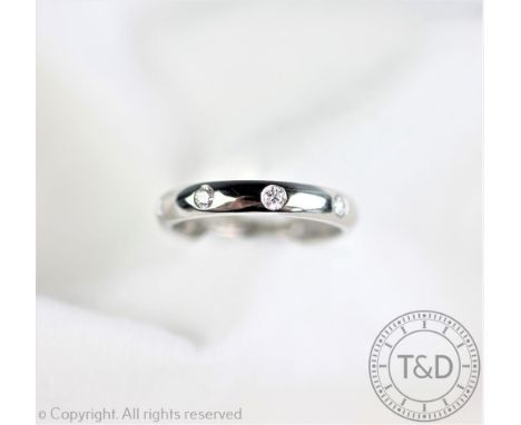 A platinum and diamond set eternity ring, the plain polished band inset with nine brilliant cut diamonds interspersed around 