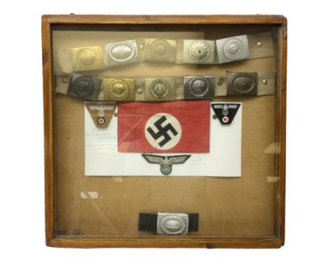 Display of eleven German belt buckles including 'SS', Party Buckle, two Army, Fire Service, two Luftwaffe, NSKK, Hitler Youth