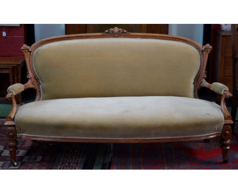 A walnut salon sofa, cresting top rail, padded back and arms, scrolling terminals, turned and fluted forelegs, brass casters.