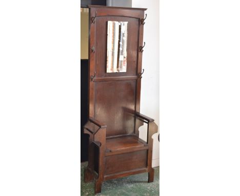 A 1930/40's oak hall stand, rectangular mirror flanked by hooks, stick stands and hinged seat enclosing storage to base.