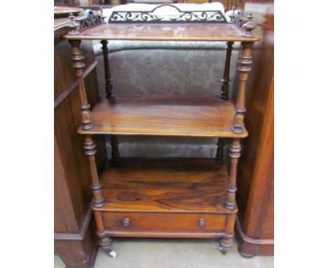 A Victorian rosewood whatnot, with a pierced three quarter gallery above three shelves and a base drawer on ceramic casters
