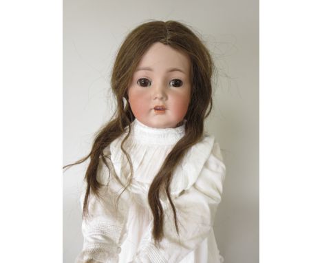 A bisque headed girl Doll with brown sleeping eyes, original wig and fully jointed body. Wearing a white babies gown. Impress