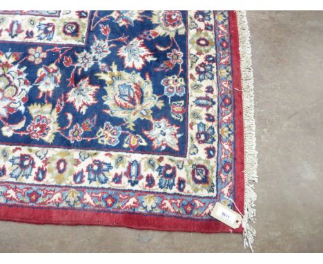 A red ground woollen Carpet with blue central stylised flower and trailing flower design with blue borders, 14ft 10in x 10ft