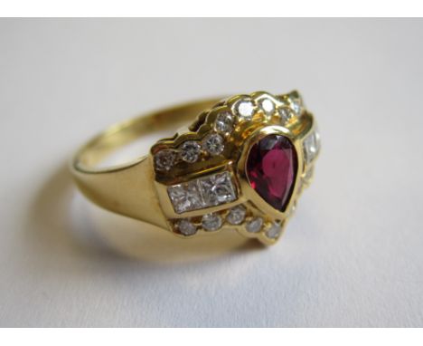 A Ruby and Diamond Ring rub-over set pear-cut ruby between four princess-cut diamonds and rows of brilliant-cut diamonds in 1